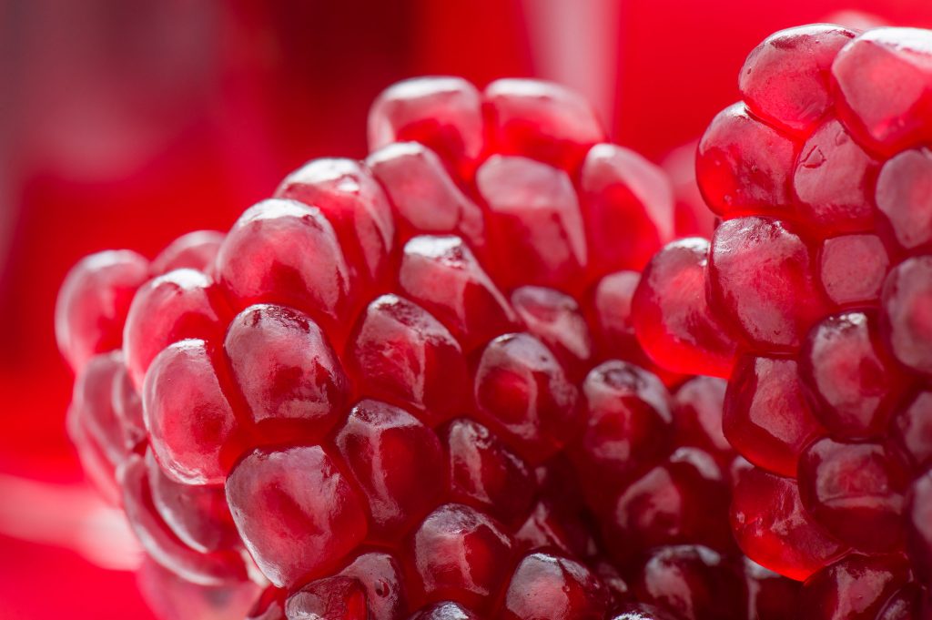 31873773 - fresh pomegranate seeds on a red background closeup